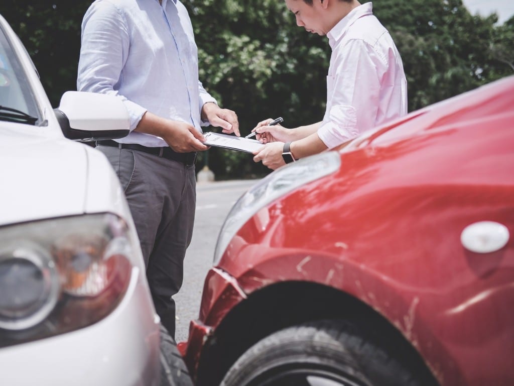 Imagen de dos personas negociando frente a un auto