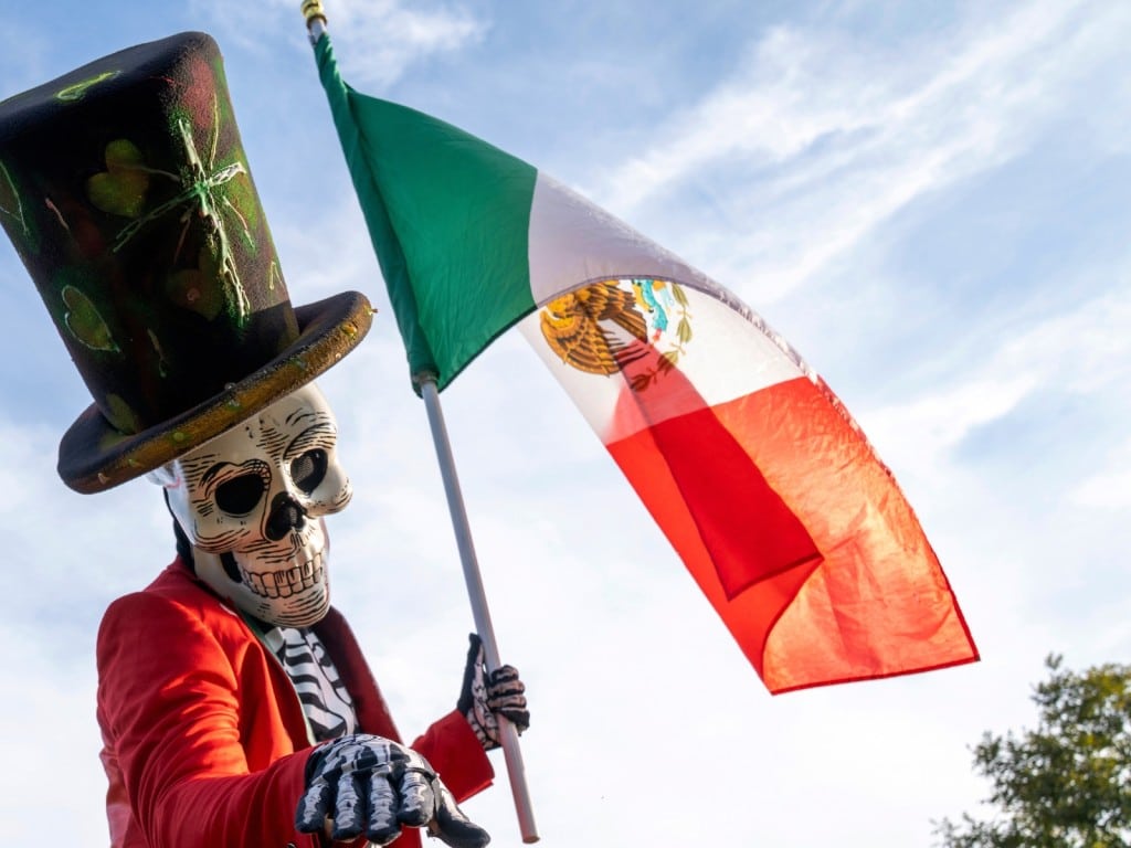 Una persona disfrazada sostiene una bandera mexicana durante las celebraciones del Día de la Independencia de México en Nueva York