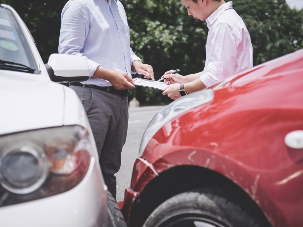 Imagen de dos personas entre dos autos que han chocado