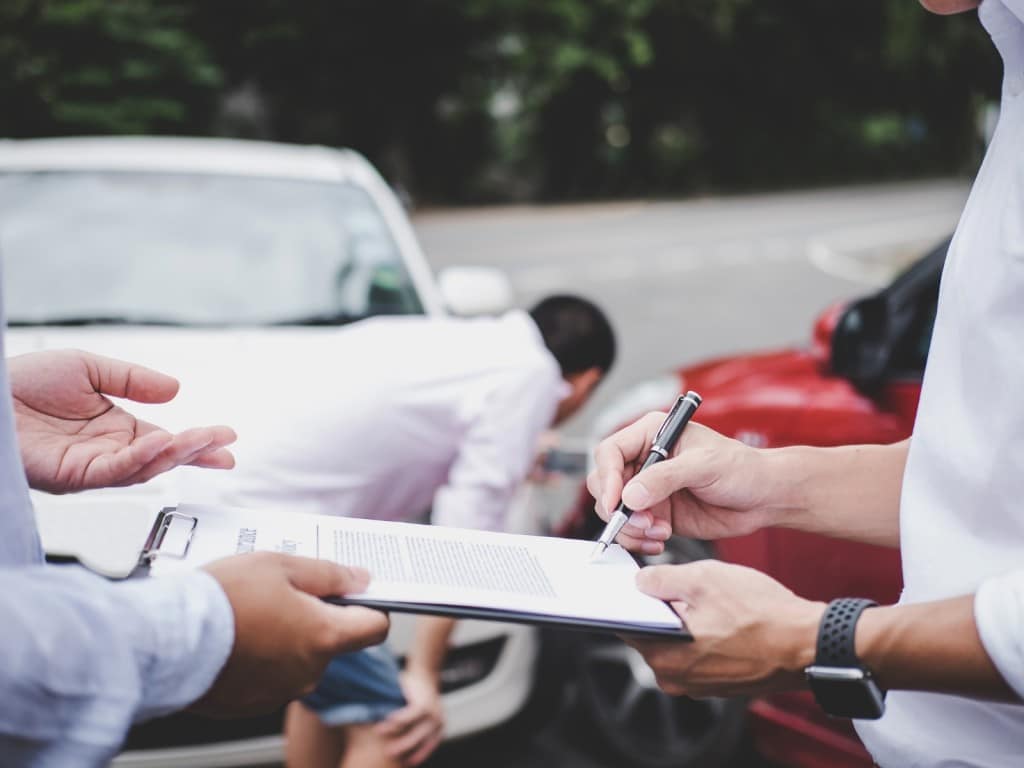 Imagen de una persona firmando el seguro de su auto luego de un choque