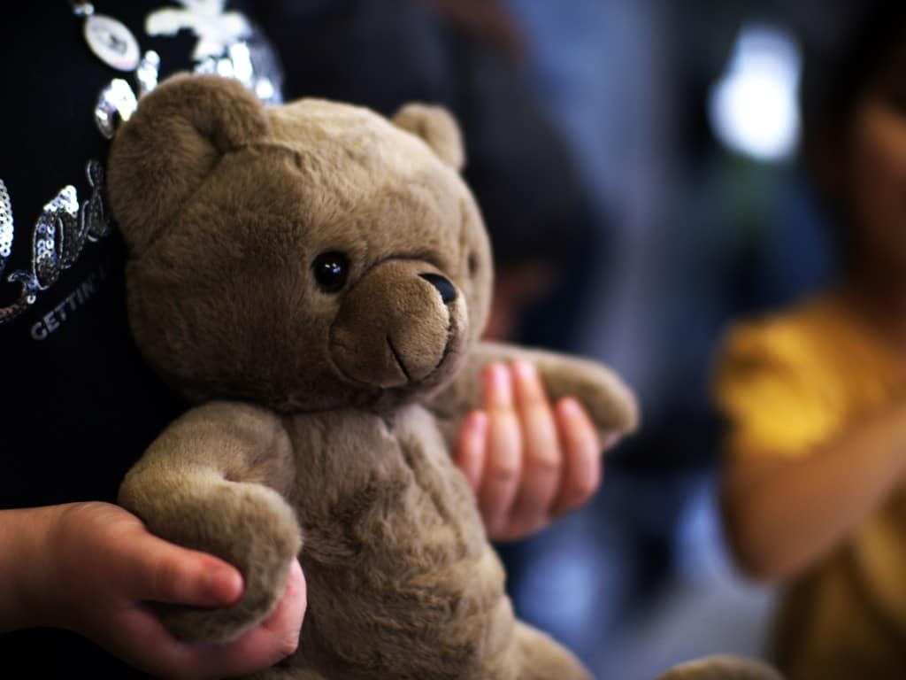 Una niña sostiene un oso de peluche