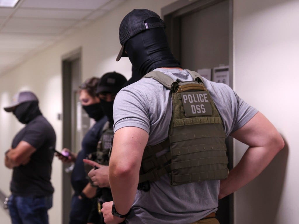 Agentes migratorios esperan en un pasillo de una corte