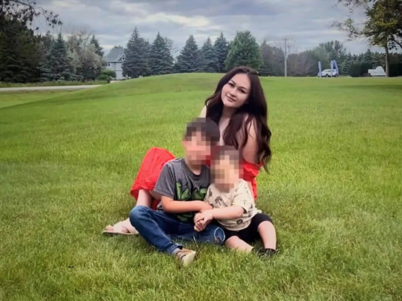 Imagen de una madre con sus dos hijos sentados en una área verde