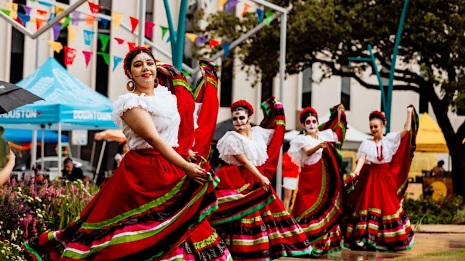 Mujeres con trajes típicos coloridos en una feria al aire libre.