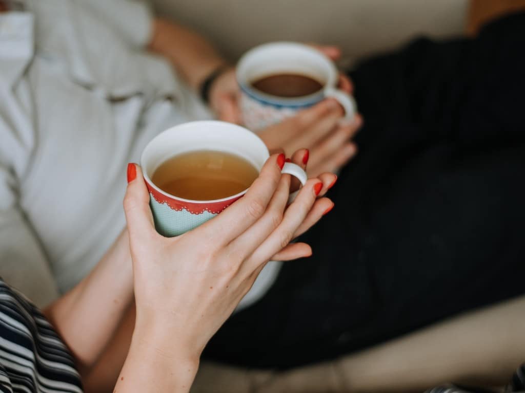 Foto de dos personas sosteniendo tasas de te