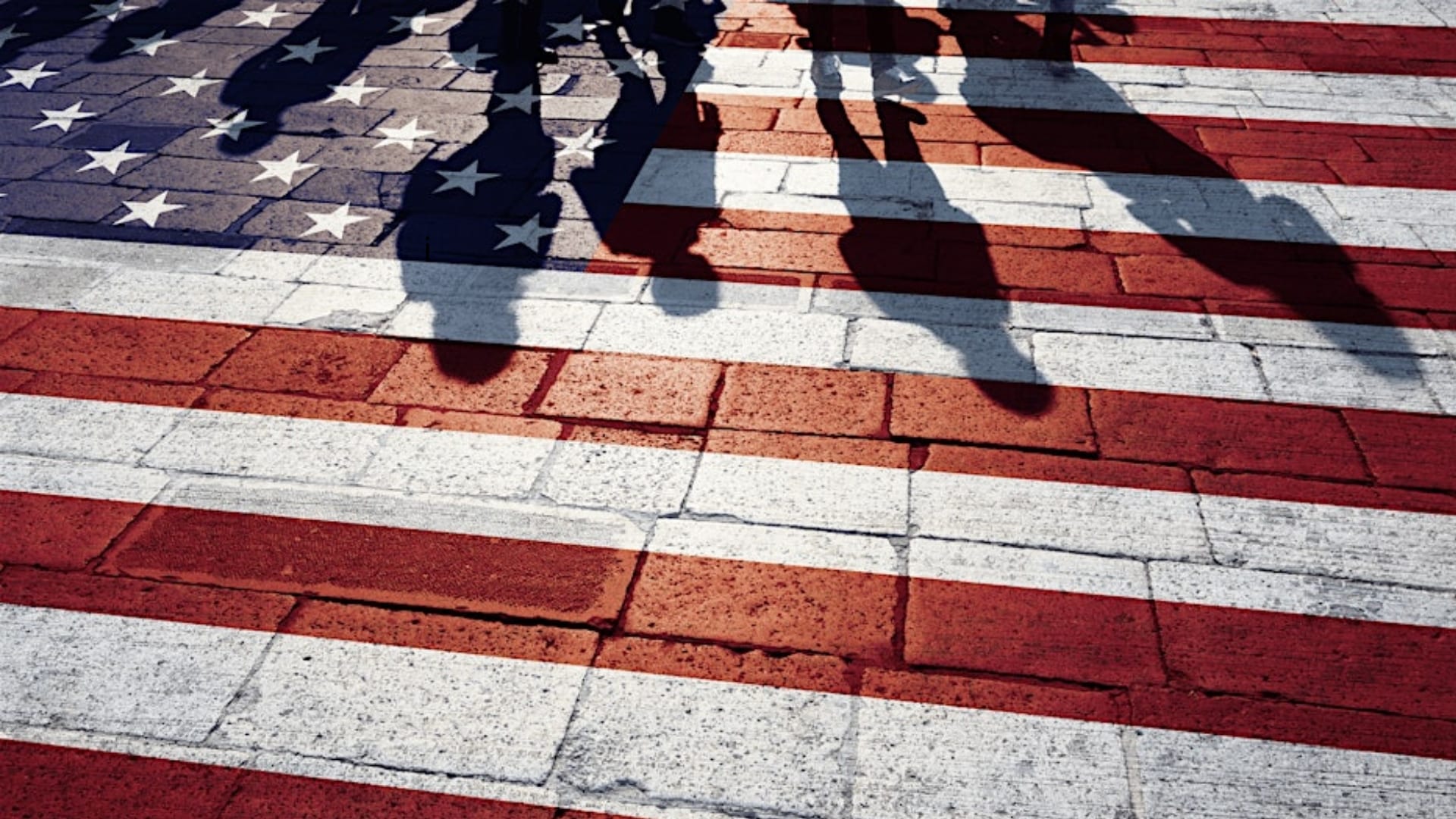 Imagen del reflejo de algunas personas sobre la bandera de Estados Unidos.