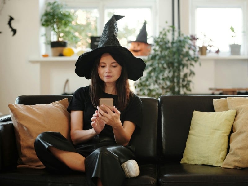 Una mujer joven con un disfraz de bruja sentada en un sofá
