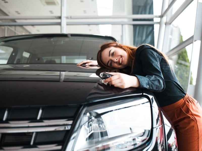 Imagen de una mujer de mediana edad con su auto nuevo