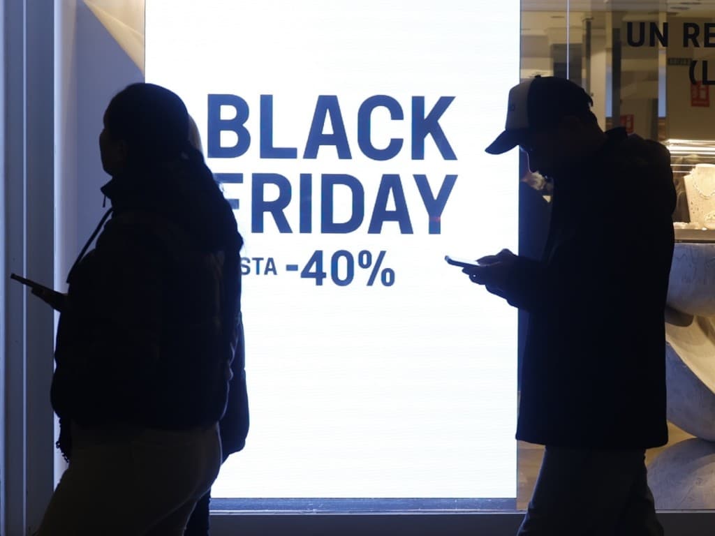 Imagen de dos personas frente a un panel de descuento por el Black Friday