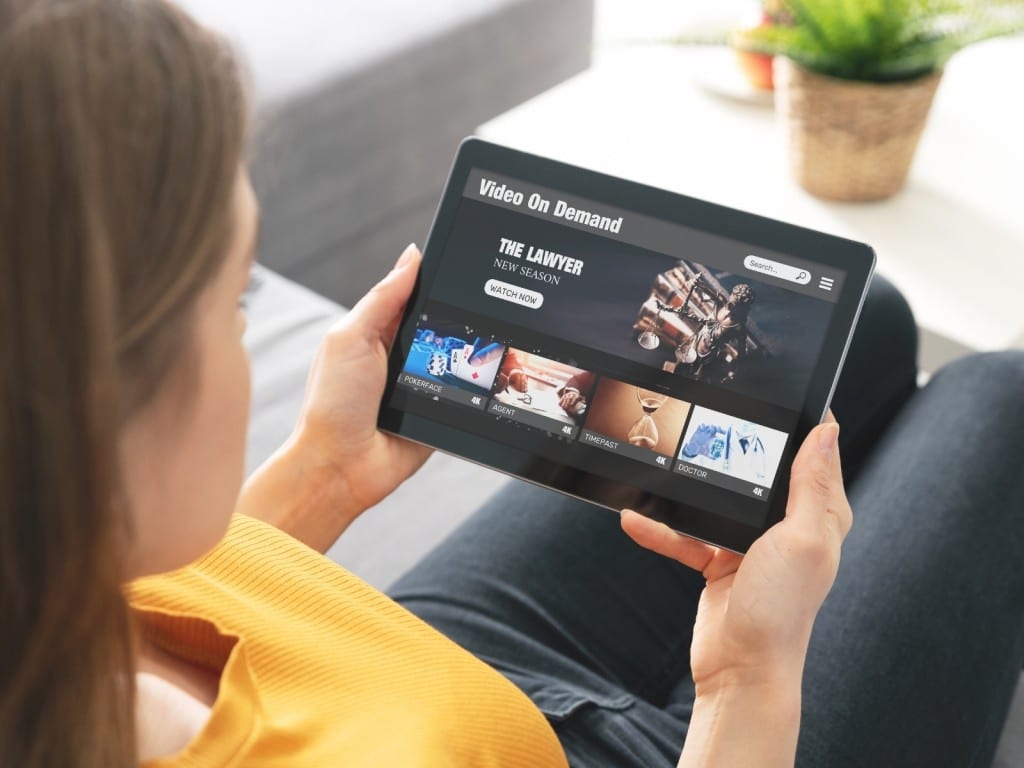 Una mujer frente a su tablet viendo un servicio de streaming