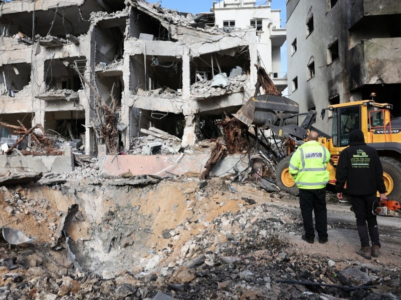 Personal de los servicios de emergencia inspecciona los daños en el lugar del impacto de un misil iraní en Tel Aviv, Israel