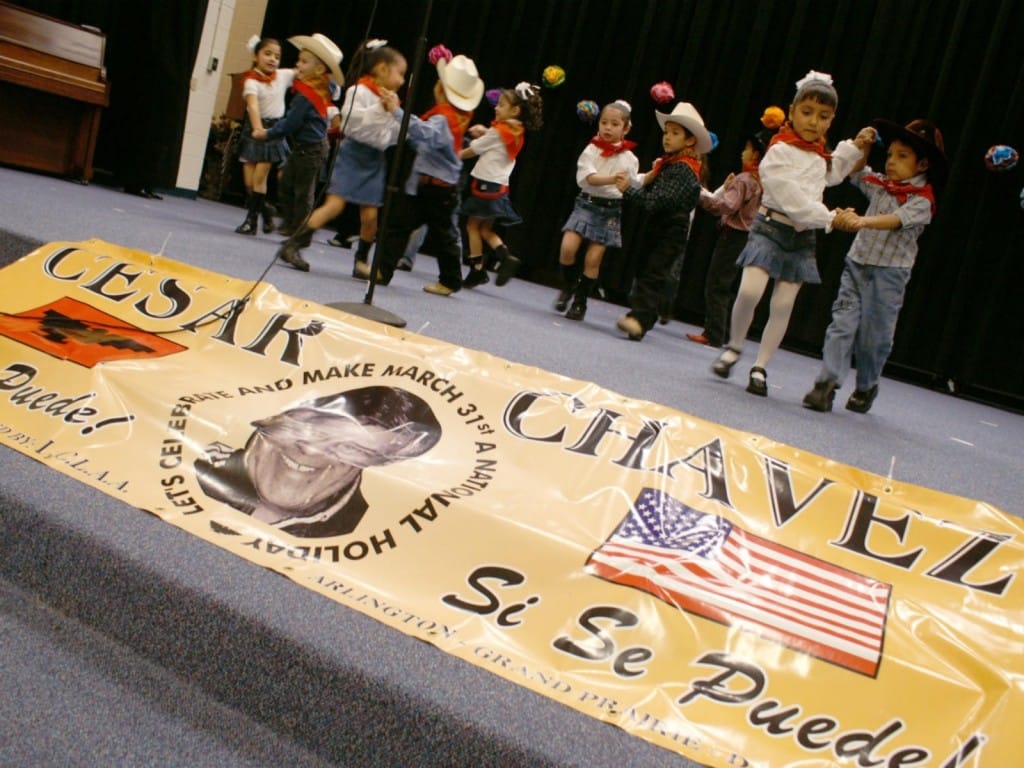 Un grupo de niños baila frente al banner de César Chávez.