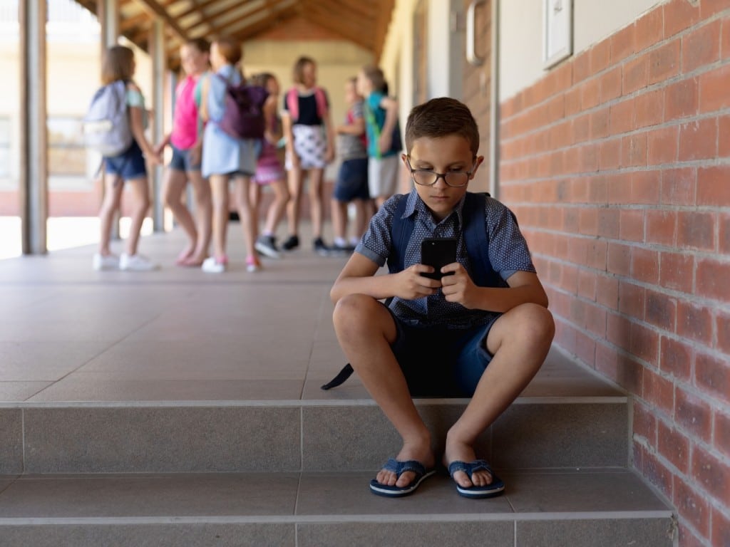 Niño con un teléfono móvil en una escuela