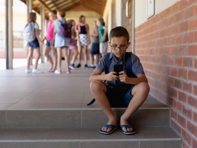 Niño con un teléfono móvil en una escuela