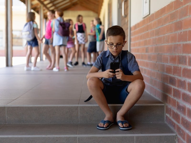Niño con un teléfono móvil en una escuela