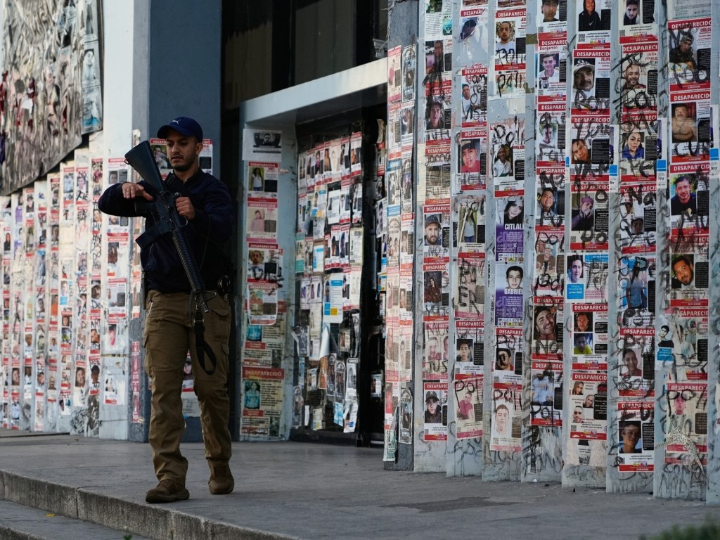 Un policía camina junto a carteles de personas desaparecidas