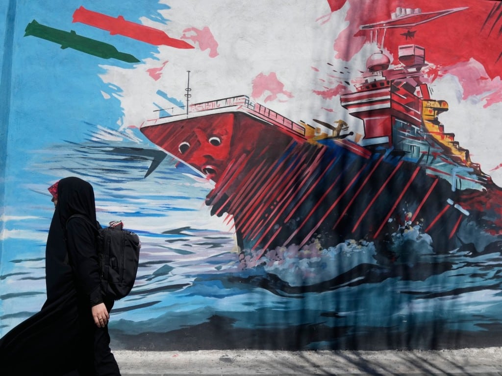 Una mujer pasa junto a un mural que muestra un portaaviones estadounidense