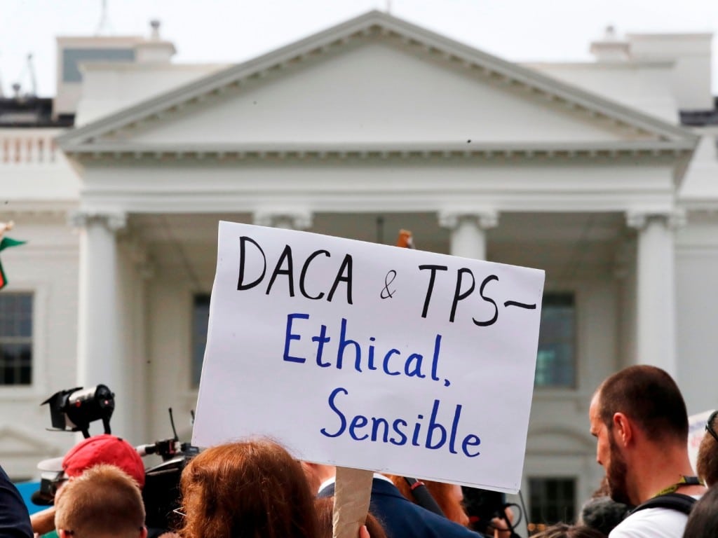 Una persona sostiene un cartel sobre su apoyo al programa DACA y al TPS