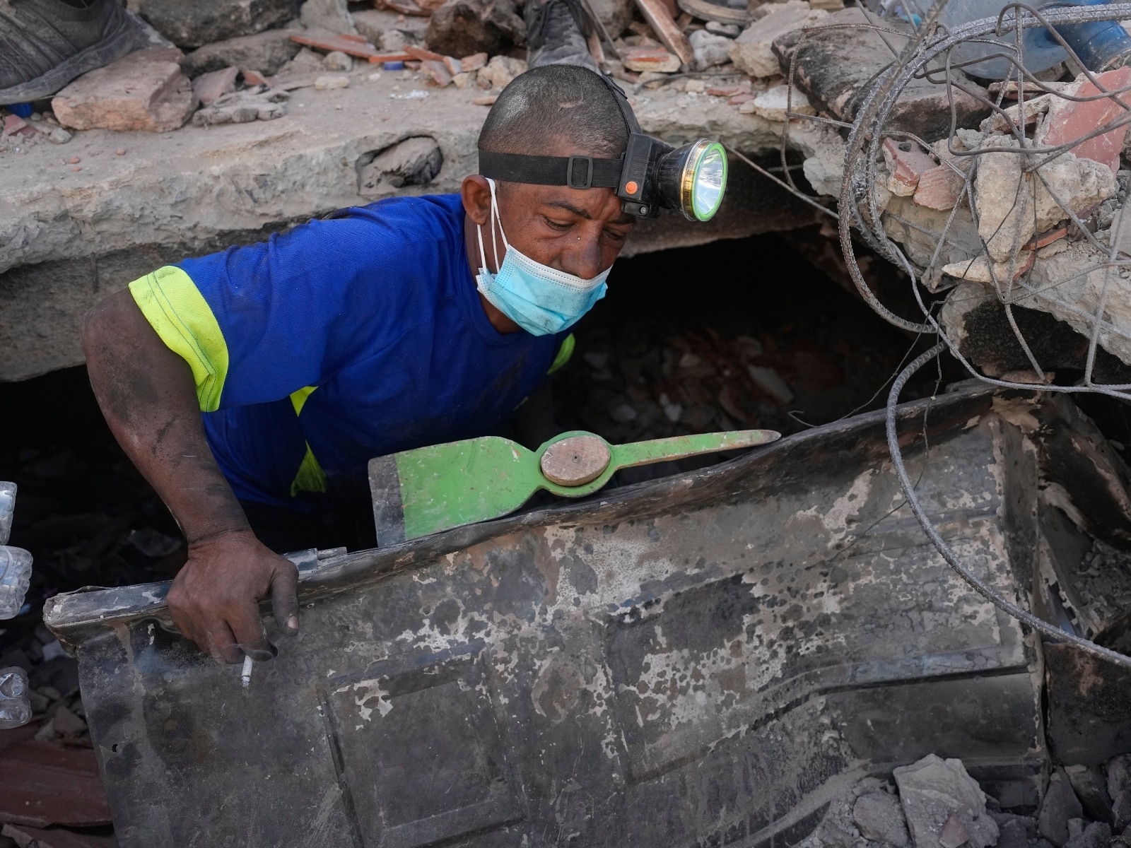 Un hombre hace una pausa para fumar mientras busca a sus familiares desaparecidos entre los escombros de su edificio