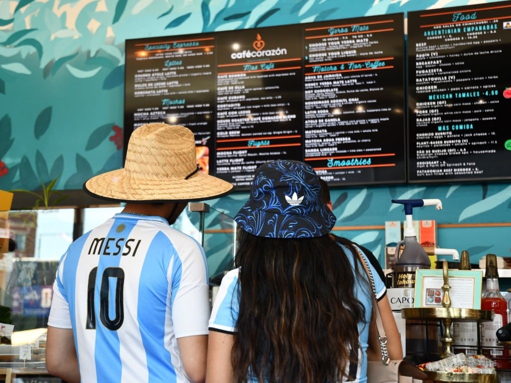 Aficionados con camisetas de la selección argentina miran la carta de bebidas en el Café Corazón