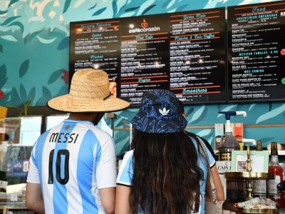 Aficionados con camisetas de la selección argentina miran la carta de bebidas en el Café Corazón