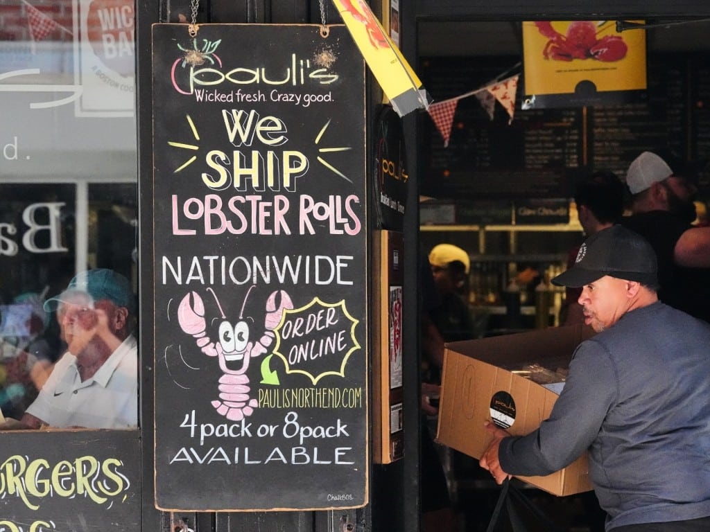 Un hombre recoge un pedido de sándwich en la tienda de sándwiches Pauli's en el barrio North End de Boston