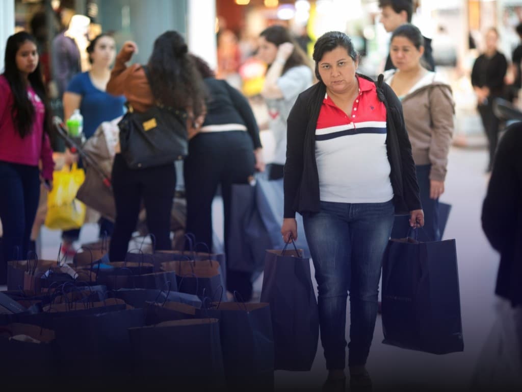 Una compradora sale de una tienda outlet con bolsas de ropa en el Dolphin Mall de Sweetwater, Florida