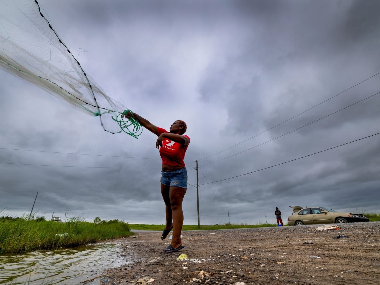 Latia Ancar practica con una amiga a lanzar una red bajo el cielo oscurecido antes de la tormenta tropical Bertha