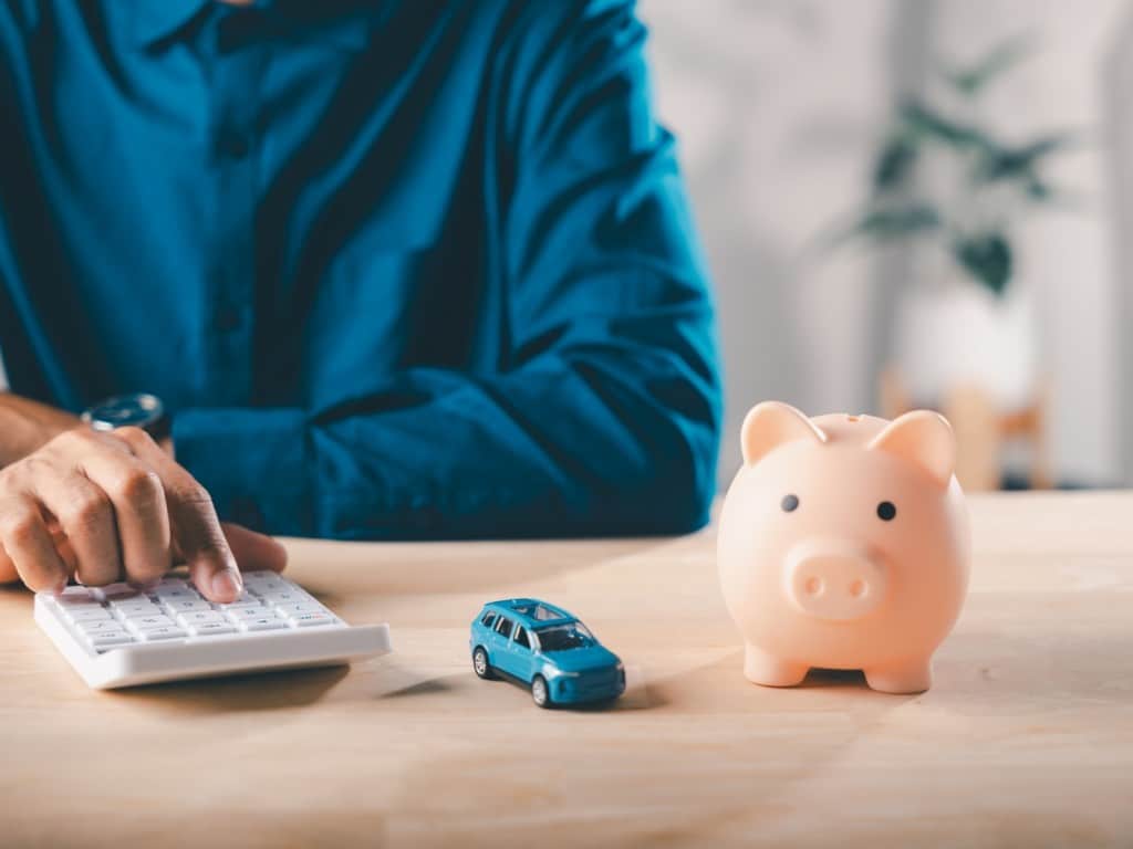 Imagen de una persona con una calculadora y al lado de una alcancía