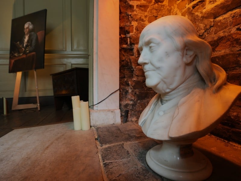 Imagen de cerca de un busto de mármol y un retrato de Benjamin Franklin