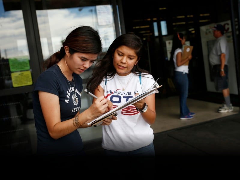 Fabiola Vejar (derecha), registra a Stephanie Cardenas para votar frente a un supermercado latino en Las Vegas