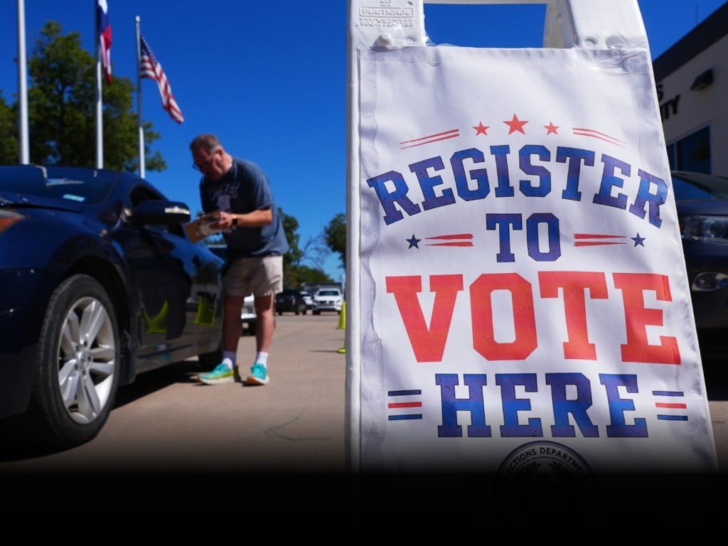 Un voluntario ayuda a un conductor a registrarse para votar en Dallas, Texas