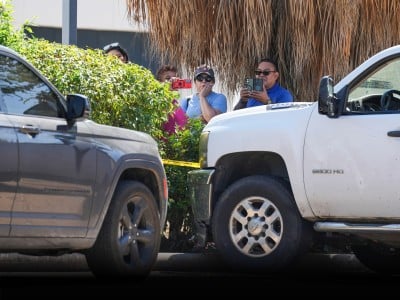Varias personas observan mientras policías del condado Harris trabajan en el lugar cerca de dos vehículos