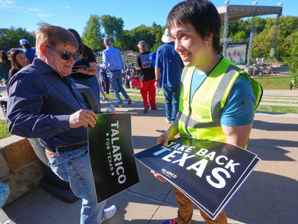 El voluntario Jason Stevens, a la derecha, entrega carteles de campaña