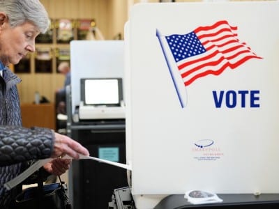Una mujer revisa su cartilla de votación antes de procesarla por el escáner
